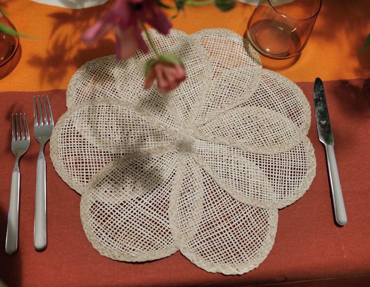 Handwoven Iraca Palm Placemat in natural color, artisan-made in Colombia, styled on an orange and rust table setting
