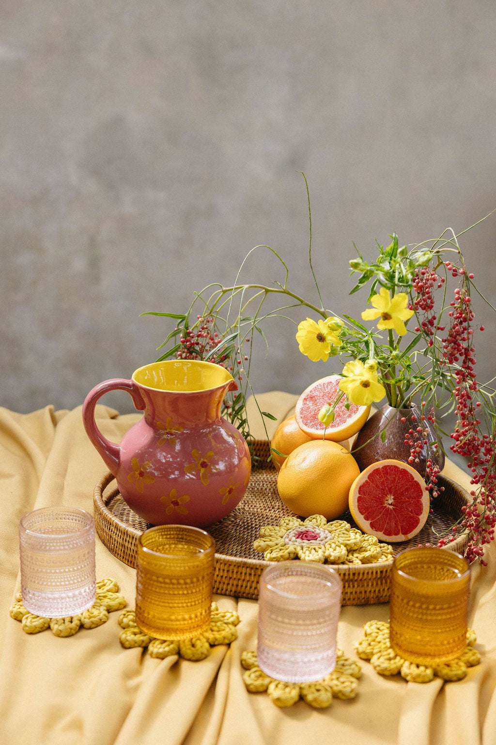 Table setting with pink ceramic jug and yellow flower drink coasters