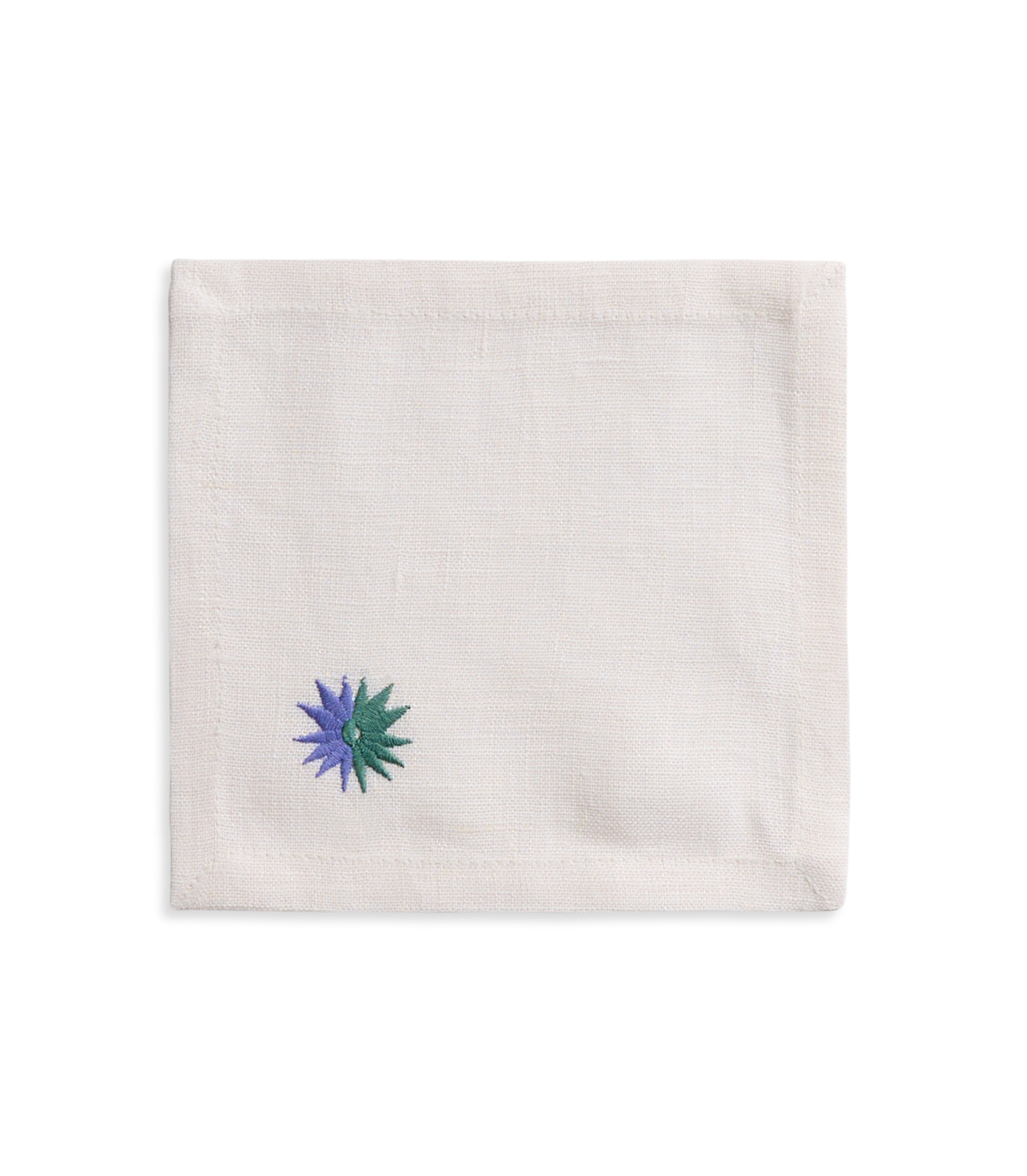 White linen cocktail napkin with green and purple corner embroidery.