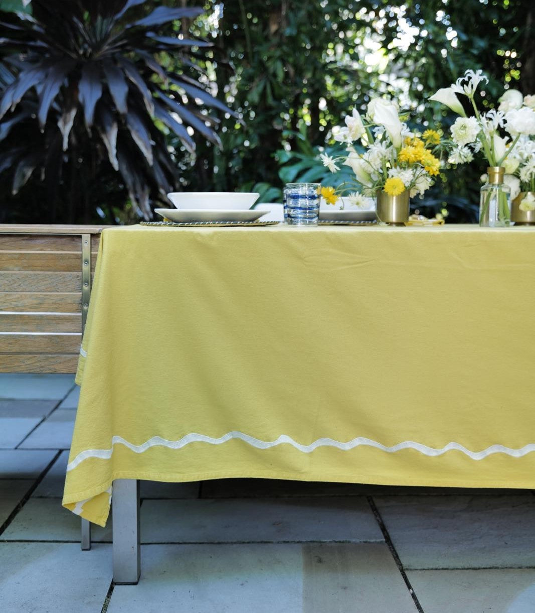 Yellow tablecloth on a table with floral arrangements outdoors