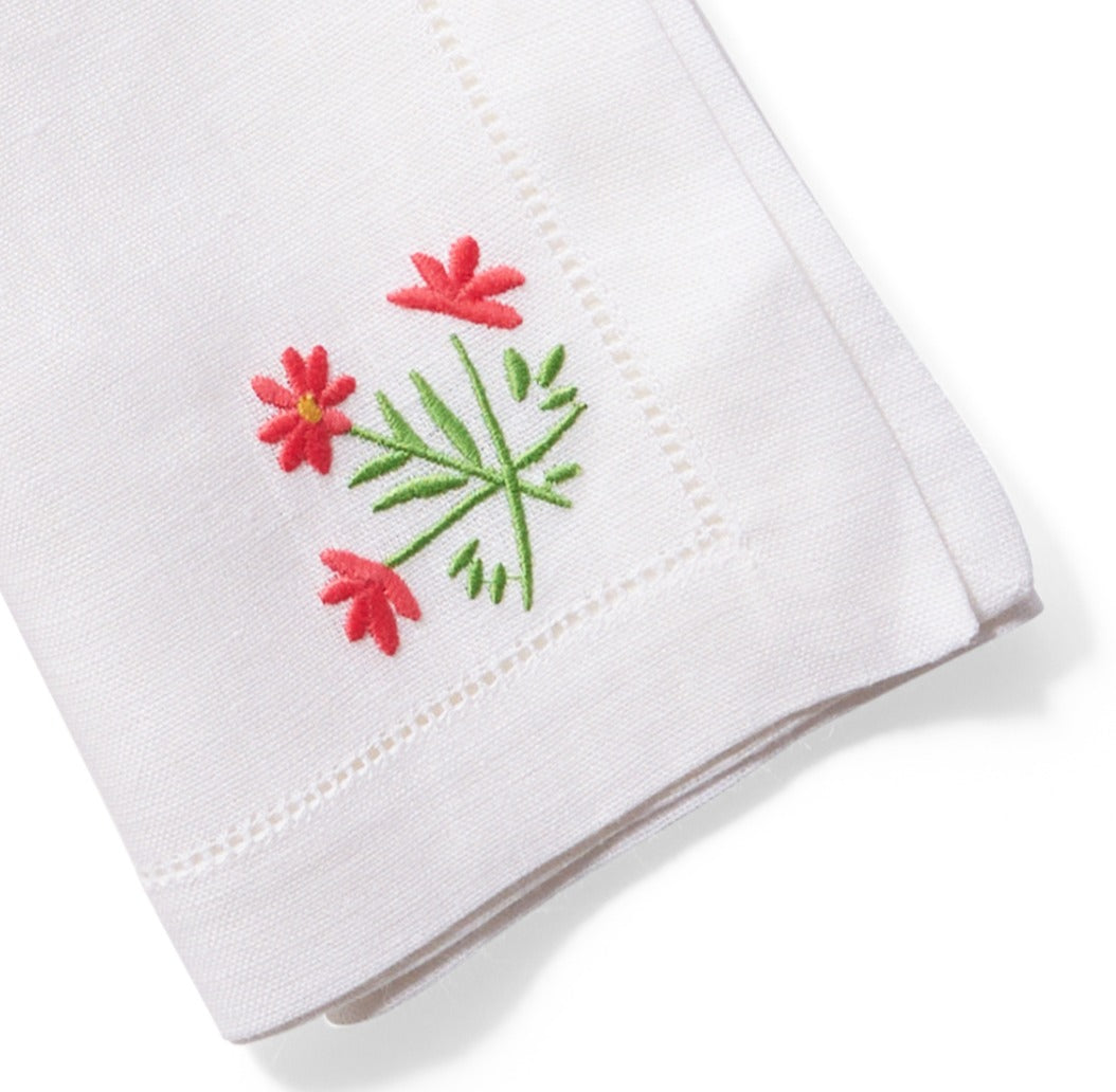 Close up image of flower embroidery on white linen dinner napkin