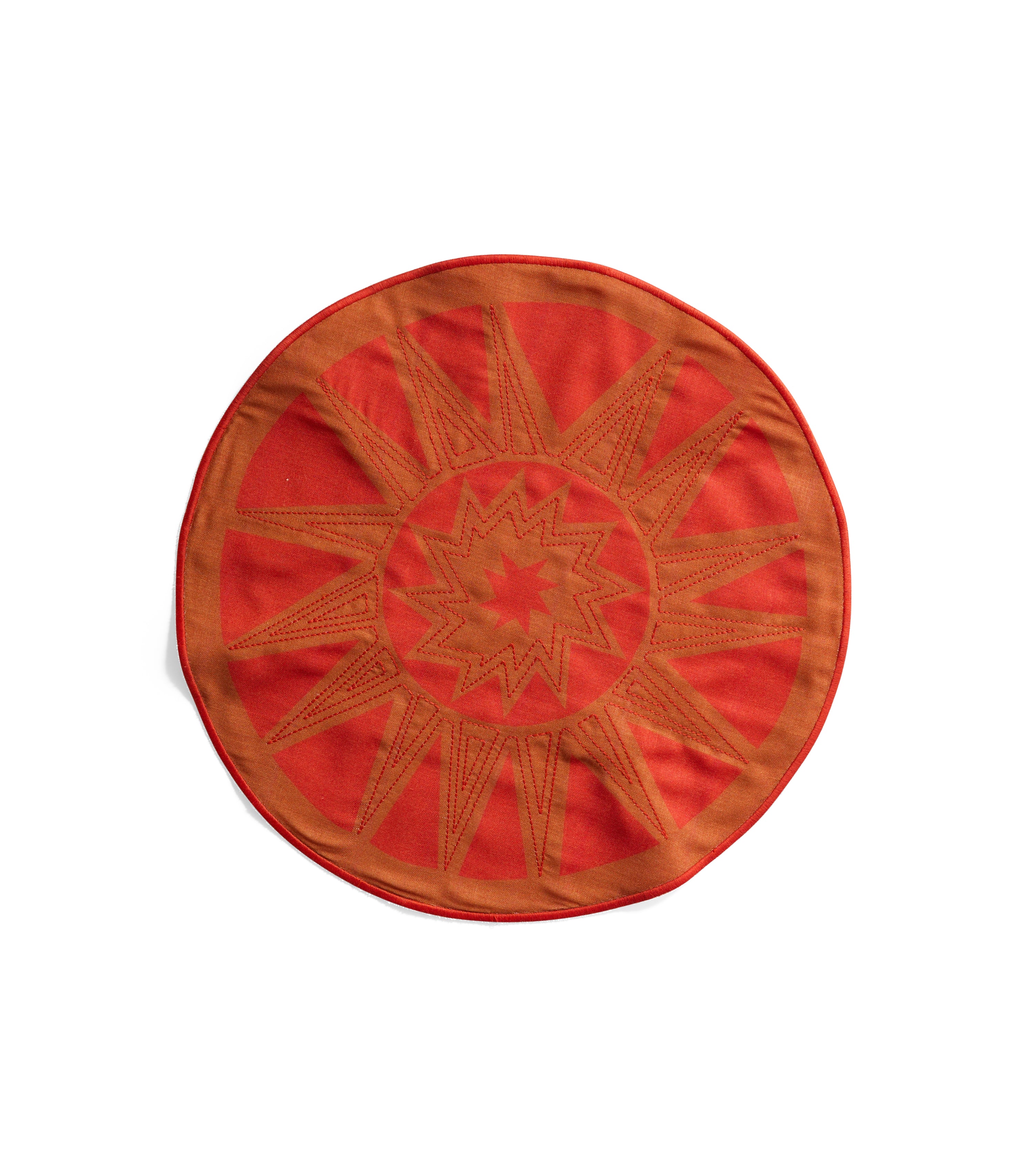 Round orange linen placemat resembling a sun with print and embroidery